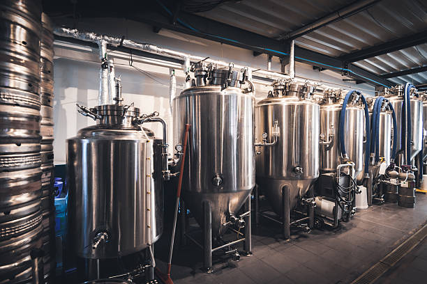istock Stainless steel fermentation tanks standing in a row inside French craft microbrewery production area 2249785953
