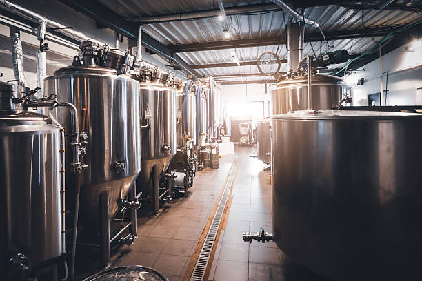 istock Stainless steel fermentation tanks aligned in sunny craft microbrewery production hall in France 2249785956