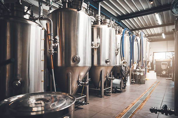 istock Stainless steel fermentation tanks aligned in sunny craft microbrewery production hall in France 2249785971
