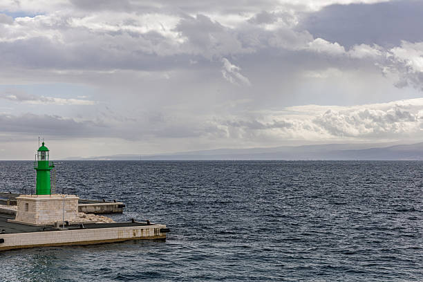 istock Green Lighthouse At Pier By Calm Sea Under Cloudy Sky And Stone Jetty 2249788977