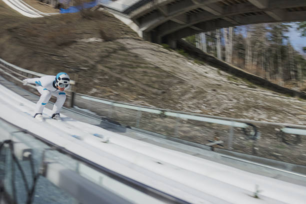 Ski jumper in the inrun, from the top of the ski jump, skiing down in a crouched position. Slovenia and ski sports destination concepts.