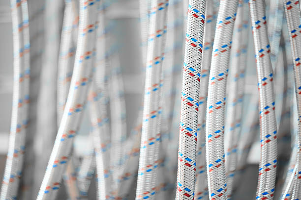 Flexible water supply hoses in metal braid hanging vertically as textured background