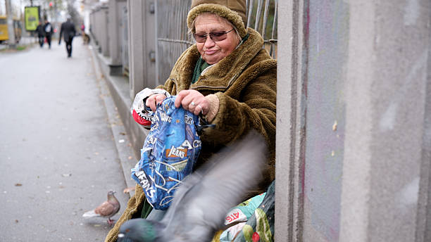 An elderly woman sits on the sidewalk, sharing moments with nearby pigeons. Kyiv, Ukraine, November 26, 2025.