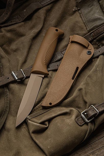istock Brown fixed-blade tactical or survival knife with its sheath on a canvas bag. 2249805538