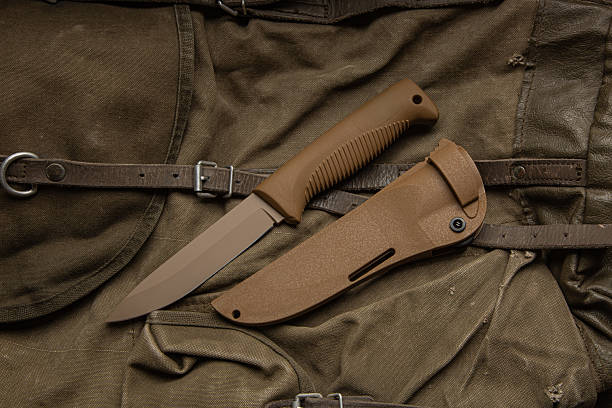 istock Brown fixed-blade tactical or survival knife with its sheath on a canvas bag. 2249805542