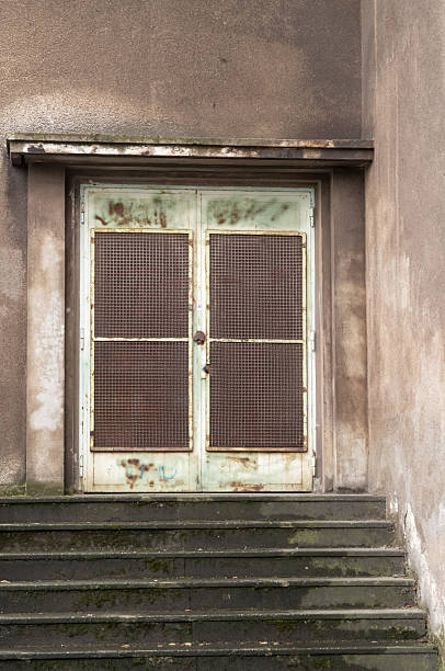 istock Old rusty metal door protecting access to a building with concrete stairs 2249805802