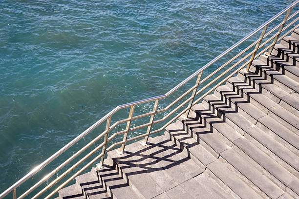 A modern architectural steps leading into the sea with calm waters and a serene atmosphere, showcasing urban design harmony with nature.