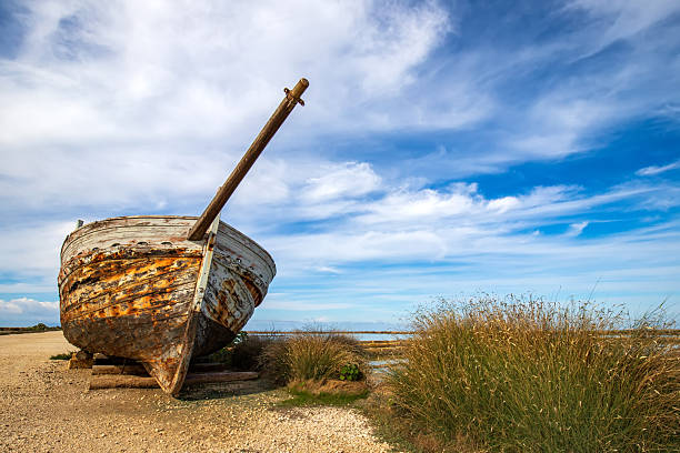 low-angle shot of a derelict wooden fishing boat resting on a sandy shoreline