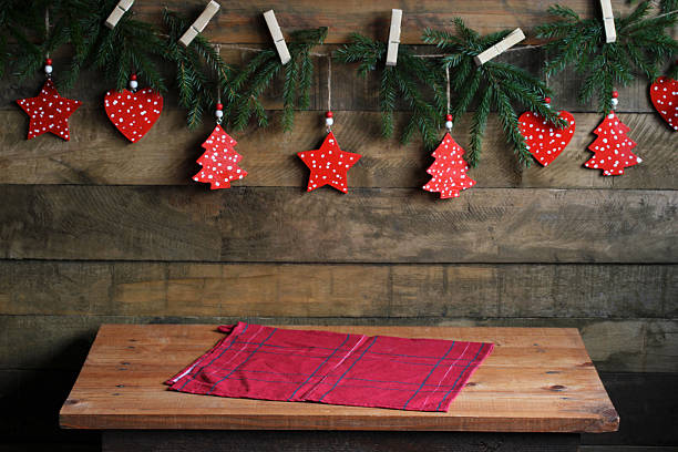 Wooden table with a red napkin in a rustic setting with diy christmas garland and ornaments
