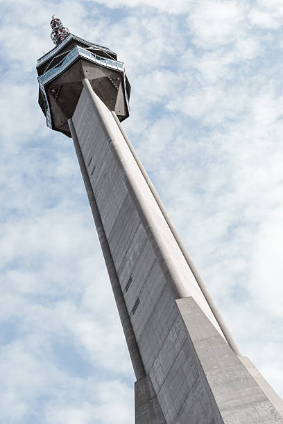 Low-angle view of the concrete brutalist Avala tower against a cloudy blue sky, Belgrade, Serbia.