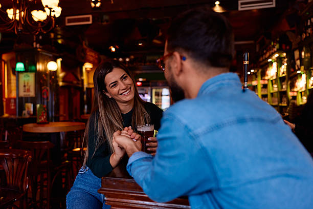 istock Young couple enjoying romantic date in cozy bar holding hands 2249814468