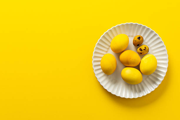 istock A decorative plate holds several yellow Easter eggs, symbolizing spring and renewal, alongside a couple of speckled quail eggs, all against a vibrant yellow background 2249819509