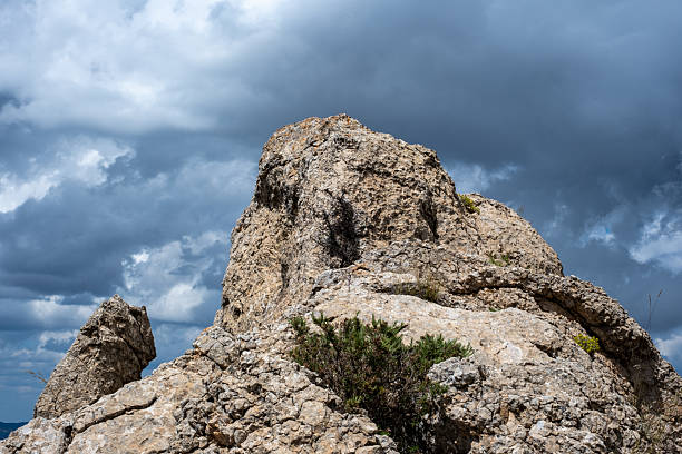 Majestic rocky cliff under dramatic cloudy sky capturing nature's raw beauty.