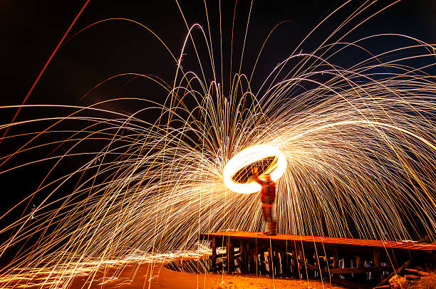 istock Fire Spinning Performance With Bright Sparks And Circular Flame Trails At Night On Pier. Creative Long Exposure Photography Fun 2249827583