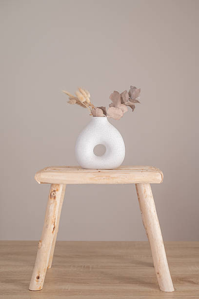 istock Ceramic vase and wooden stool in a neutral interior 2249829889