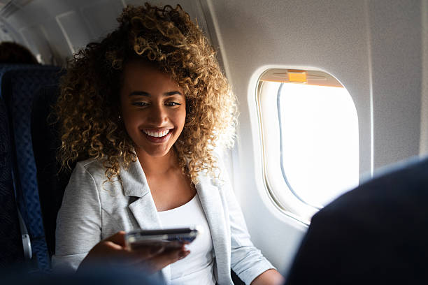 istock Happy woman smiling while using smartphone during airplane flight near window 2249834455
