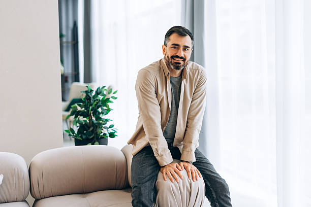 istock Smiling bearded man smiling confidently sitting on comfortable sofa in modern living room at home 2249841516