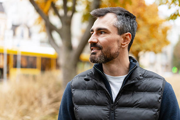 istock Handsome smiling man looking away in autumn city park copy space 2249843596