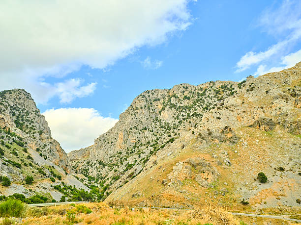 Crete, Greece captures a striking valley and canyon amid rugged mountains, sparse greenery, and a vivid blue sky. This Mediterranean landscape conveys outdoor adventure, nature, and travel allure, ideal for nature, scenery, and travel stock uses.