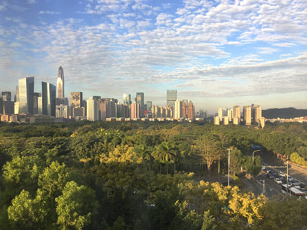 Just beyond a giant city park, the sun rises over the modern skyline of Shenzhen, China. 2018