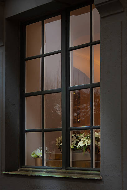 istock A window offering a view of the illuminated interior, decorated for Christmas with white poinsettias. 2249853064