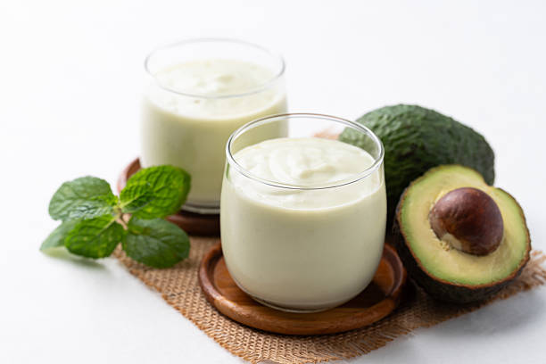 Avocado smoothie with milk in glass and avocado fruit on white background