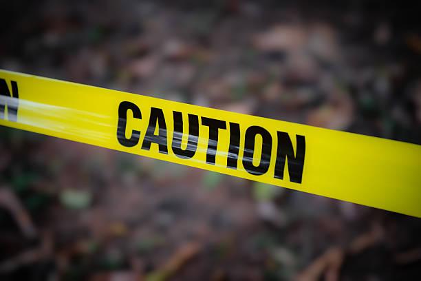 Caution tape on a metals poles in front of a brick wall.
