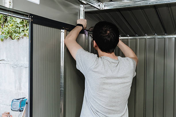 istock A craftsman installs a door on a metal barn using an electric screwdriver. 2249857376