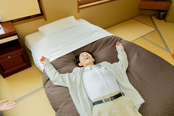 A middle-aged woman arriving at her accommodation and lying down on the bed