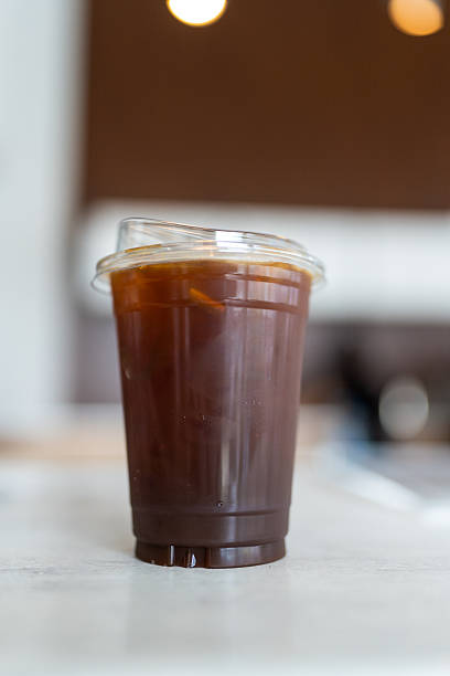 Iced americano coffee in a disposable glass on white table.