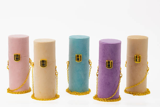 A row of five small containers with different colors and designs. The containers are lined up next to each other, and they all have a chain hanging from them. The chain is gold