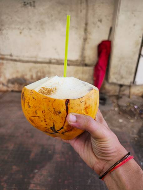 istock Fresh Tender Coconut with Straw Held in Hand on Street Side Background 2249864481