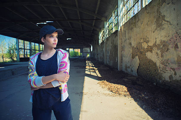 Young female hip hop dancer standing in abandoned building on a sunny day.
