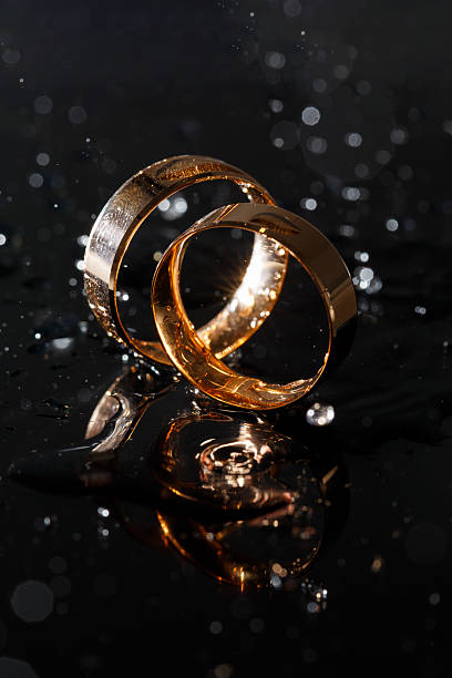 istock Wedding rings with water droplets,The engagement ring set.,Beautiful silver background with wedding rings and stars 2249869640