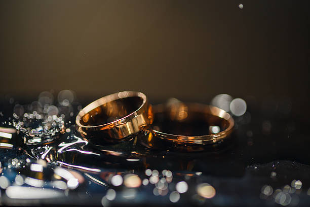 istock Wedding rings with water droplets,The engagement ring set.,Beautiful silver background with wedding rings and stars 2249876805