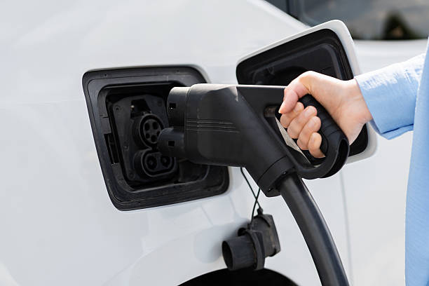 istock Person Charging Electric Vehicle with a Charging Cable and Plug 2249883663