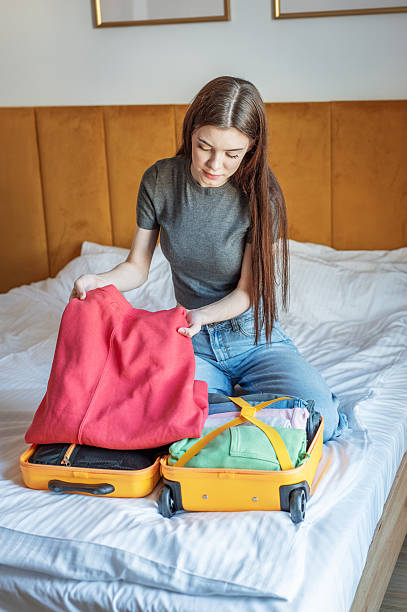 istock Young woman packing suitcase for upcoming trip on bed 2249884046