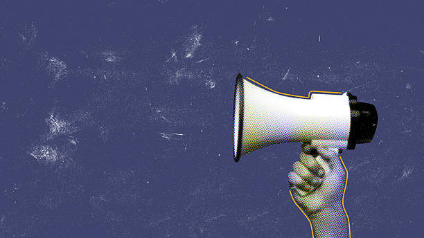 istock Hand holding a megaphone against a blue backdrop for communication and activism 2249884506