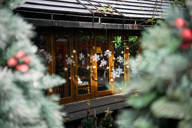 istock A festive window adorned with snowflake decorations and golden ornaments, framed by blurred Christmas greenery. 2249884740
