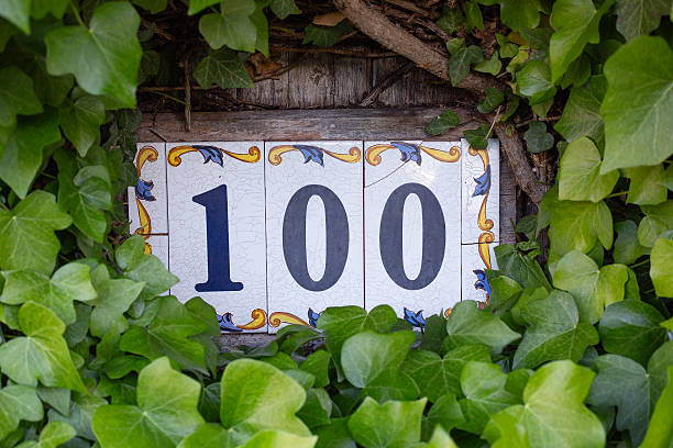 istock Number 100 depicted on three small ceramic tiles mounted on a wall 2249887100