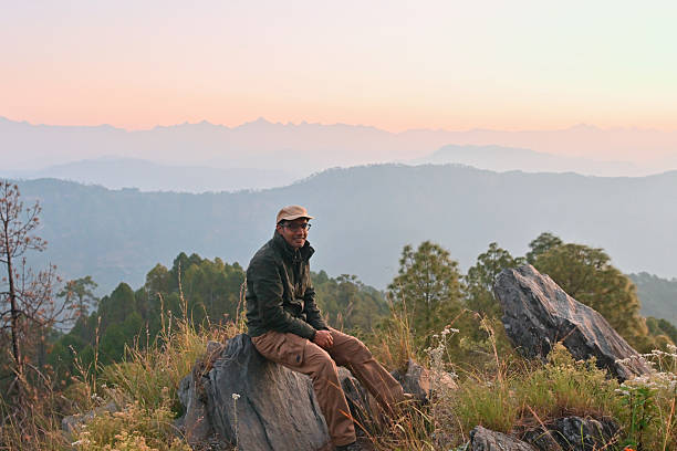 istock Man Sitting on Mountain Rock at Sunrise with Himalayan Range in the Background, Uttarakhand, India 2249887976