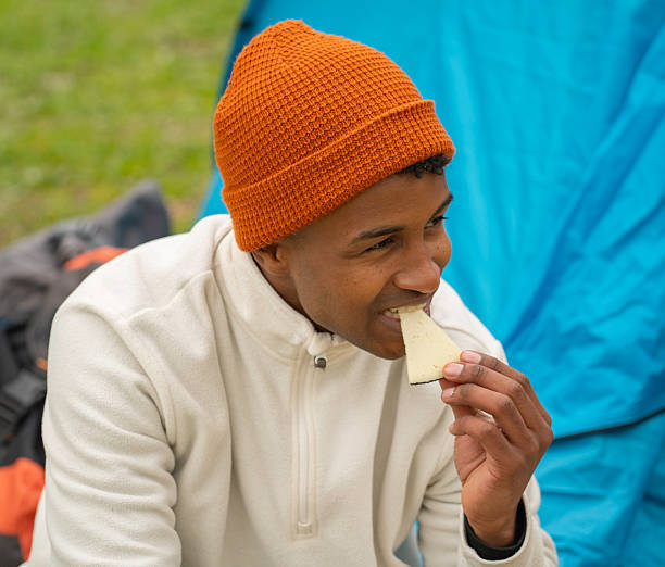 istock Young black man enjoying a piece of cheese while camping 2249888109