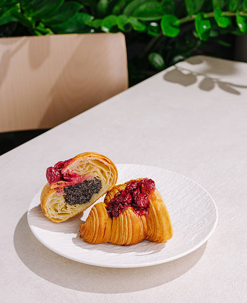 Two freshly baked croissants are displayed on a white plate