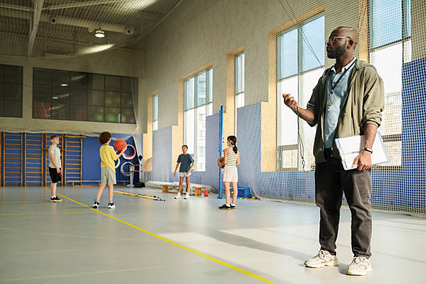 istock Black Man Coaching Diverse Children Practicing Basketball Indoors 2249893403