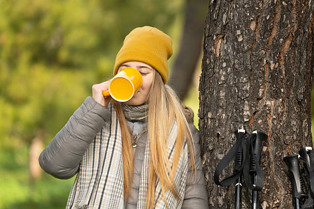 istock Hiker woman drinking hot beverage from yellow mug during autumn hike 2249896199