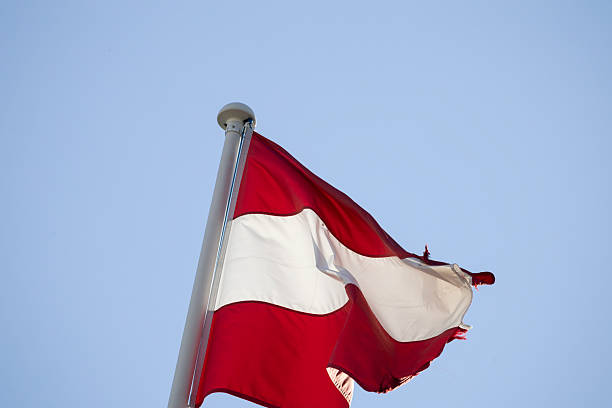 istock Austrian flag waving in wind against blue sky 2249897859