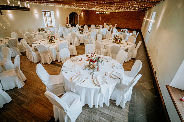 istock Elegant banquet hall set for a celebration with round tables adorned in white tablecloths, floral centerpieces, and soft lighting creating a warm, inviting atmosphere for gatherings 2249898290