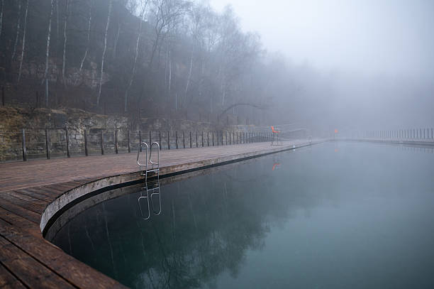 Foggy outdoor swimming pool with wooden deck and misty trees. Zakrzowek, Krakow