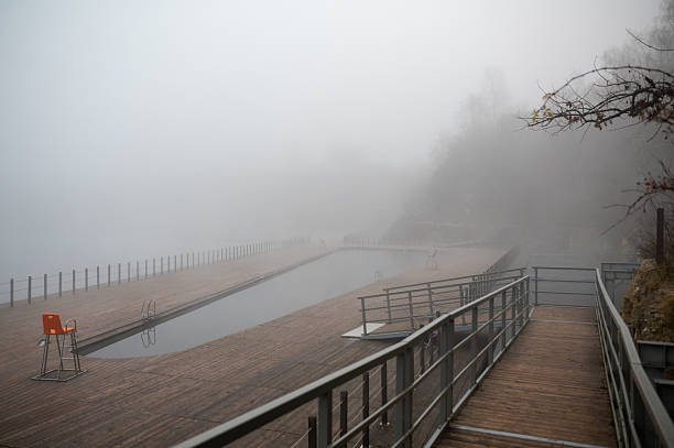 Foggy outdoor swimming pool with wooden deck and lifeguard chair. Zakrzowek, Krakow