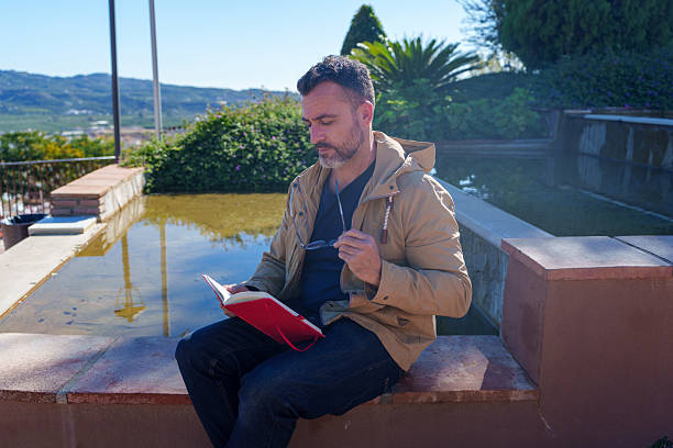 Mature man relaxing and reading book nature in park bench